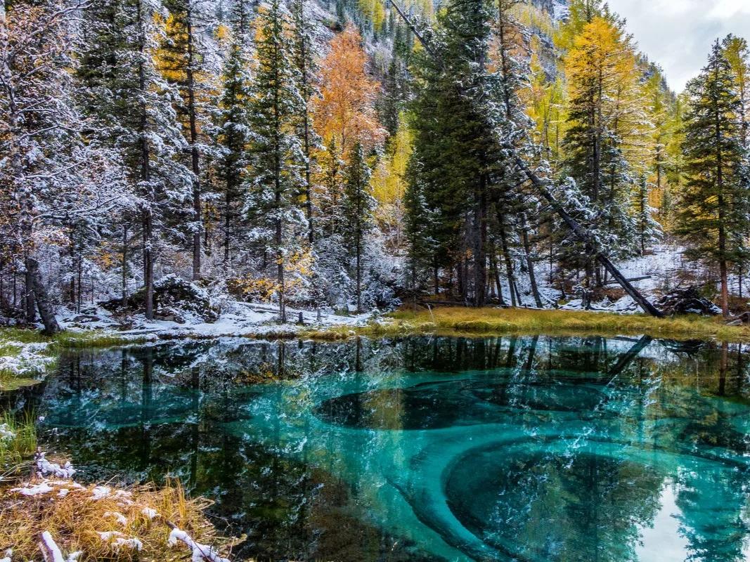 Открытая вода Гейзерного озера и снег на лесном берегу